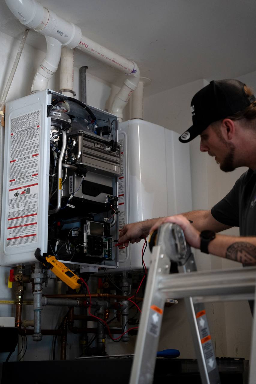 Flamingo technician servicing a wall-mounted tankless water heater